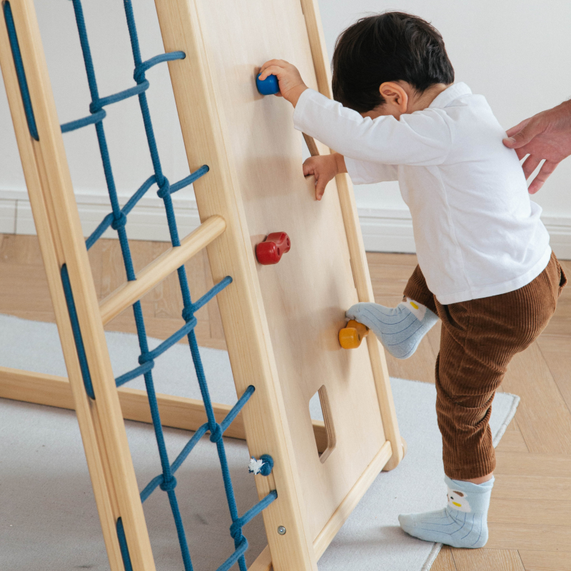 toddler climbing wooden wall structure at home